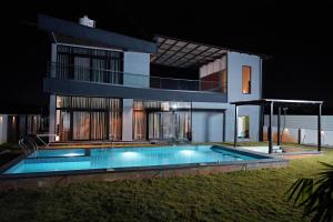a house with a swimming pool in front of it at Luxe poolside farmhouse -J House in Hyderabad