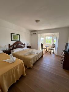 een slaapkamer met twee bedden en een tafel en stoelen bij NOVA Hotel Pinamar in Pinamar