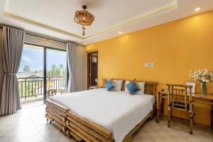 a bedroom with a large bed and a balcony at Calm House 4 Hoi An in Hoi An