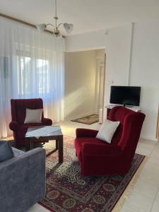 ein Wohnzimmer mit 2 roten Stühlen und einem TV in der Unterkunft Levendula vendégház in Verpelét