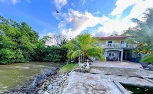 a house with a river in front of it at Casa Vista al Amatique in Puerto Barrios