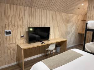 a bedroom with a television on a wooden wall at Hotel Puerto Madera in Pelluhue +38 photos