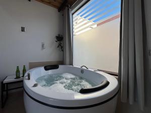 een badkuip in een badkamer met een raam bij Ofurô com hidromassagem aquecida in Guia Lopes da Laguna