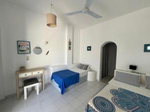 een slaapkamer met 2 bedden, een bureau en een plafondventilator bij Villa Campos Yalos beach in Ios Chora
