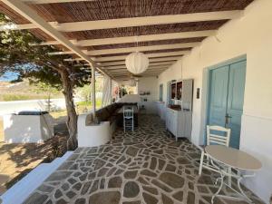 een patio met een tafel en stoelen en een boom bij Villa Campos Yalos beach in Ios Chora
