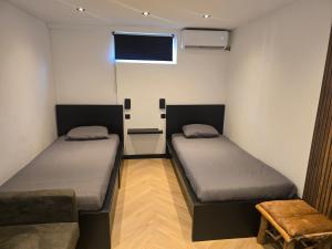 two beds in a room with a tv and a couch at ZM Tilburg in Tilburg