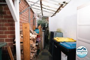 een garage met een bakstenen muur, een luifel en een stapel hout bij Ferienwohnung See Glück in Wunstorf +11 foto's