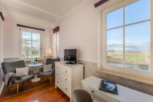 een kamer met 2 stoelen, een tv en een raam bij Hotel Villa Wahnfried Thiessow in Thiessow