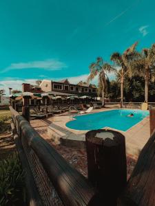 a swimming pool in front of a house with palm trees at Complejo La Yema in Miramar