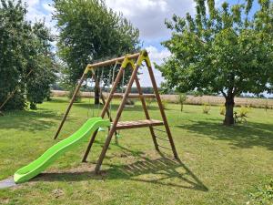 een schommel met een groene glijbaan in een park bij Gîte de la Petite Forge in Clévilliers