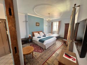 une chambre avec un lit, une table et une télévision dans l'établissement La Cour du Bailli Suites & Spa, à Bergheim