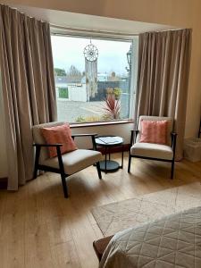 a bedroom with two chairs and a large window at Malahide Guest Rooms in Malahide