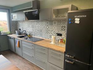 eine Küche mit einem schwarzen Kühlschrank und einer Spüle in der Unterkunft Charmante Fachwerkhaushälfte mit Sauna in Rosche + 7 Fotos