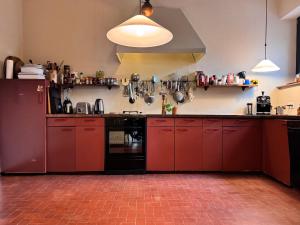 a kitchen with red cabinets and a black appliance at Casa d'epoca con giardino 5 min da Locarno in Minusio