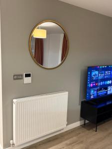 een spiegel aan de muur naast een radiator en een tv bij Chalk in Moffat