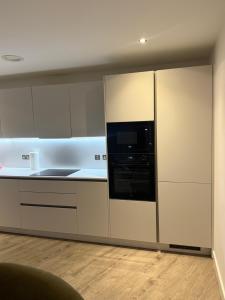 een keuken met witte kasten en een zwarte magnetron bij Chalk in Moffat