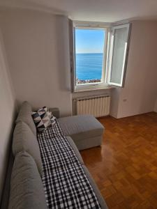 a living room with a couch and a large window at Apartmaji Trije Valovi in Piran
