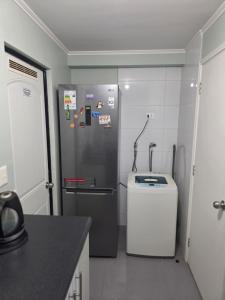a kitchen with a refrigerator and a trash can at Villa Parque Cordillera 1 in Chillán