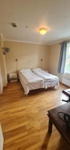 een slaapkamer met een groot bed en een houten vloer bij Sauda Bed & Breakfast in Sauda