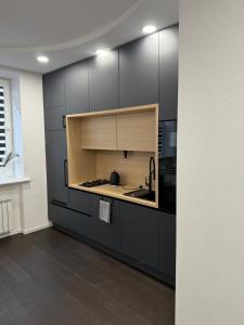 a kitchen with black cabinets and a sink at Turgaus 10 in Klaipėda