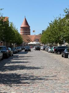a cobblestone street with parked cars and a clock tower at Turgaus 10 in Klaipėda