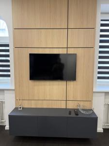 a living room with a tv on a wall at Turgaus 10 in Klaipėda +3 photos
