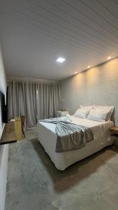 a bedroom with a large white bed and a television at Vila Gaheri in São Miguel dos Milagres