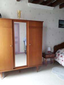 a wooden cabinet with a mirror in a bedroom at Gite à Lulu in Châteauvieux