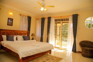 een slaapkamer met een bed, een stoel en een raam bij CALM SUITES KAMPALA in Kampala +5 foto's