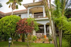 een huis met palmbomen ervoor bij CALM SUITES KAMPALA in Kampala