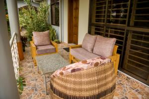 een veranda met 2 stoelen en een bank bij CALM SUITES KAMPALA in Kampala