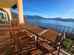 a wooden table and chairs on a balcony with a view of a lake at Lago Maggiore - Traumbalkon mit Seeblick & Pool und 2 SZ in Oggebbio