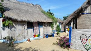 a group of houses with thatched roofs and a fence at A&Y Wild Camp Ghana in Keta