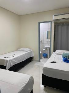 a bedroom with two beds and a bathroom with a shower at Estrela de davi in Goiânia +11 photos