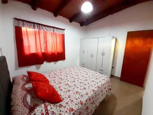 a bedroom with a bed with red pillows on it at Brisas de las Sierras in Tanti