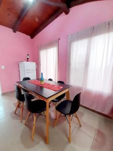 een tafel en stoelen in een kamer met een roze muur bij Brisas de las Sierras in Tanti