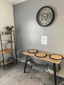 une table avec des chaises et une horloge sur le mur dans l'établissement Le logis Katia, à Saumur