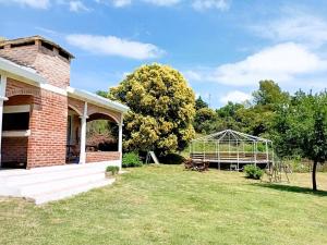 a greenhouse in a yard next to a brick house at Cabañas Las Pasionarias in Tanti