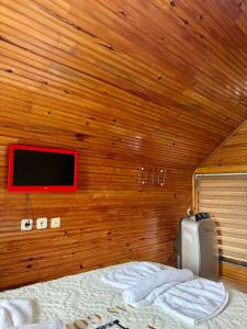 a bedroom with a wooden wall with a bed and a tv at Isgobya Sumela Monastery 106 in Macka
