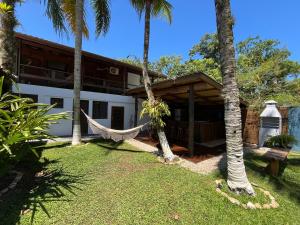 een hangmat voor een huis met palmbomen bij Pousada Nalu - Camburi in São Sebastião