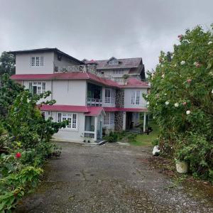a large pink and white house with a yard at Vajrayogini Inn in Pedong