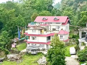 a large house with a pink roof on a hill at Vajrayogini Inn in Pedong