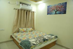 een klein bed in een kamer met een schilderij aan de muur bij ShivAOM Family Homestay in Ujjain