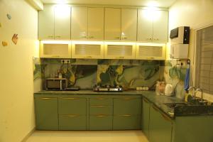 een keuken met groene kasten en een aanrecht bij ShivAOM Family Homestay in Ujjain