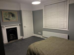 ein Schlafzimmer mit einem Kamin, einem Bett und einem Fenster in der Unterkunft Seaside 3 bed terraced house in Hastings