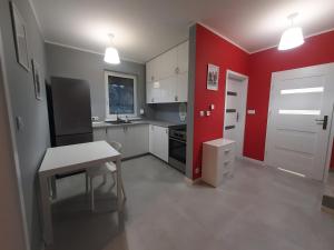 een keuken met rode muren, witte kasten en een tafel bij Czapury in Czapury