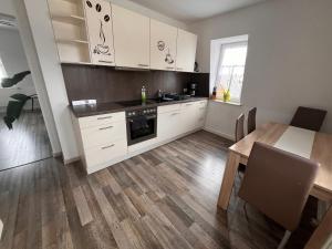 eine Küche mit weißen Schränken und einem Holztisch in der Unterkunft Ferienwohnung Unger in Großhartmannsdorf