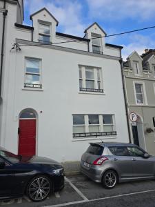 twee auto's geparkeerd voor een wit huis bij 2 Bed Apartment with Harbour Views Apt 2 in Cobh