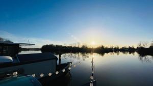 a boat docked on a lake with the sun setting at Hausboot Lütje in Hamburg +3 photos
