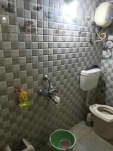a bathroom with a toilet and a green bucket at Keshav in Bhuj